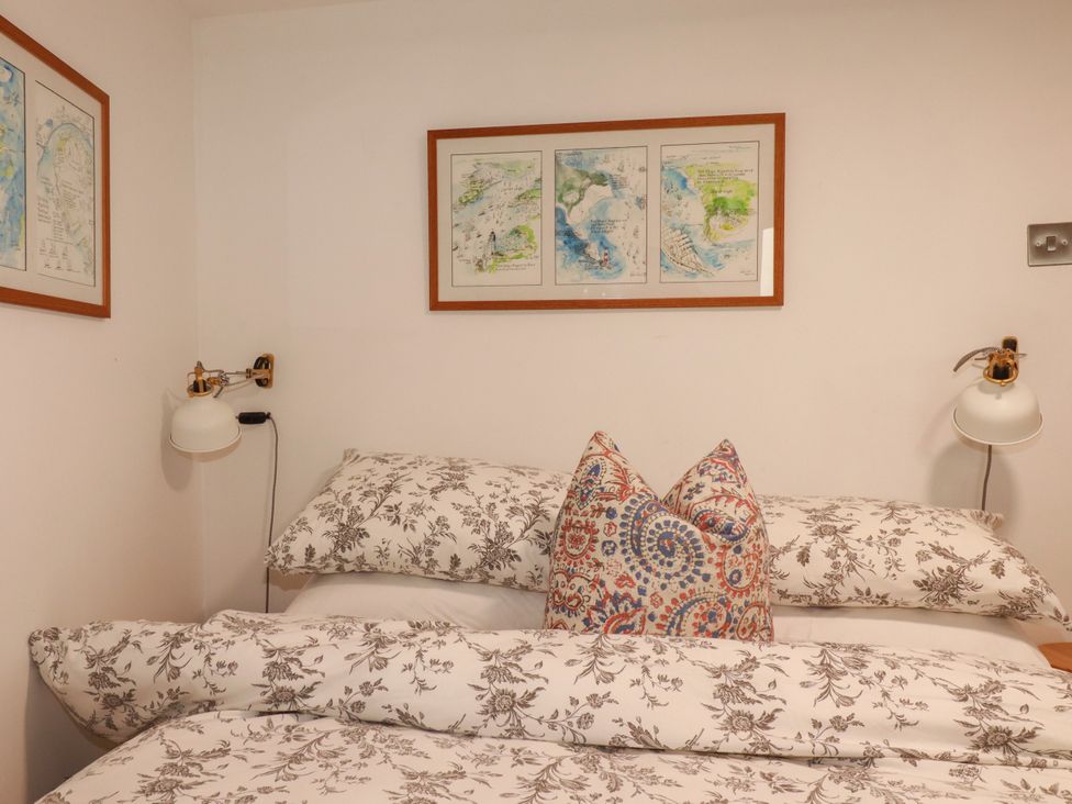 A bedroom with a bed and artwork on the wall at Dolphin Cottage in Falmouth