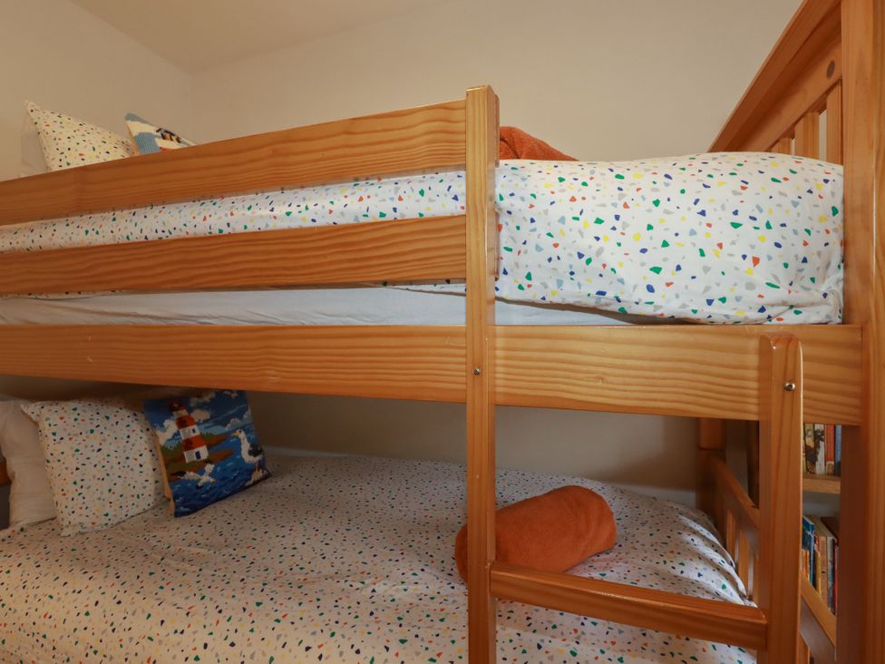 A bunk bed with pillows and orange towel at Dolphin Cottage in Falmouth