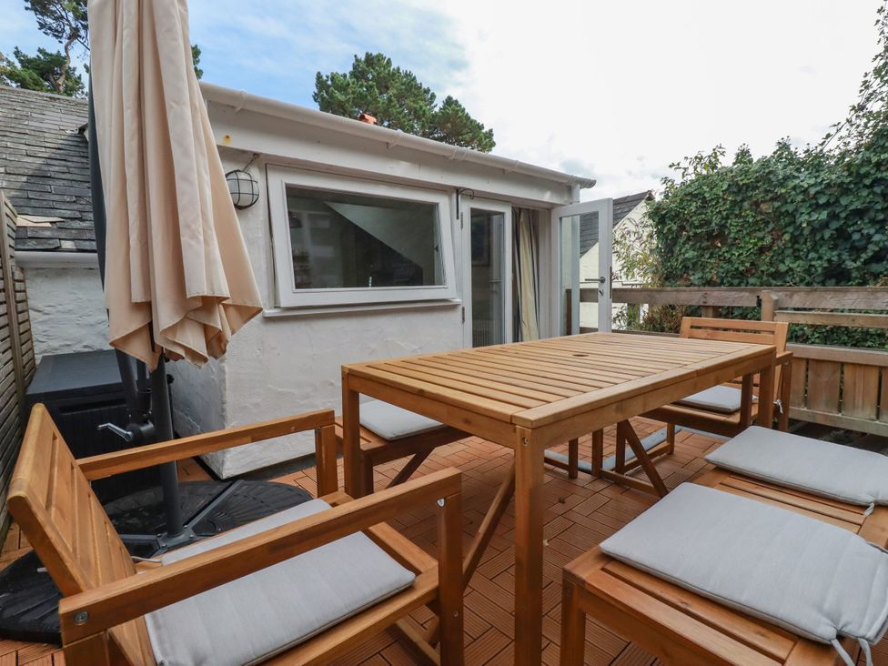 An outdoor dining area with wooden table and chairs at Dolphin Cottage in Falmouth