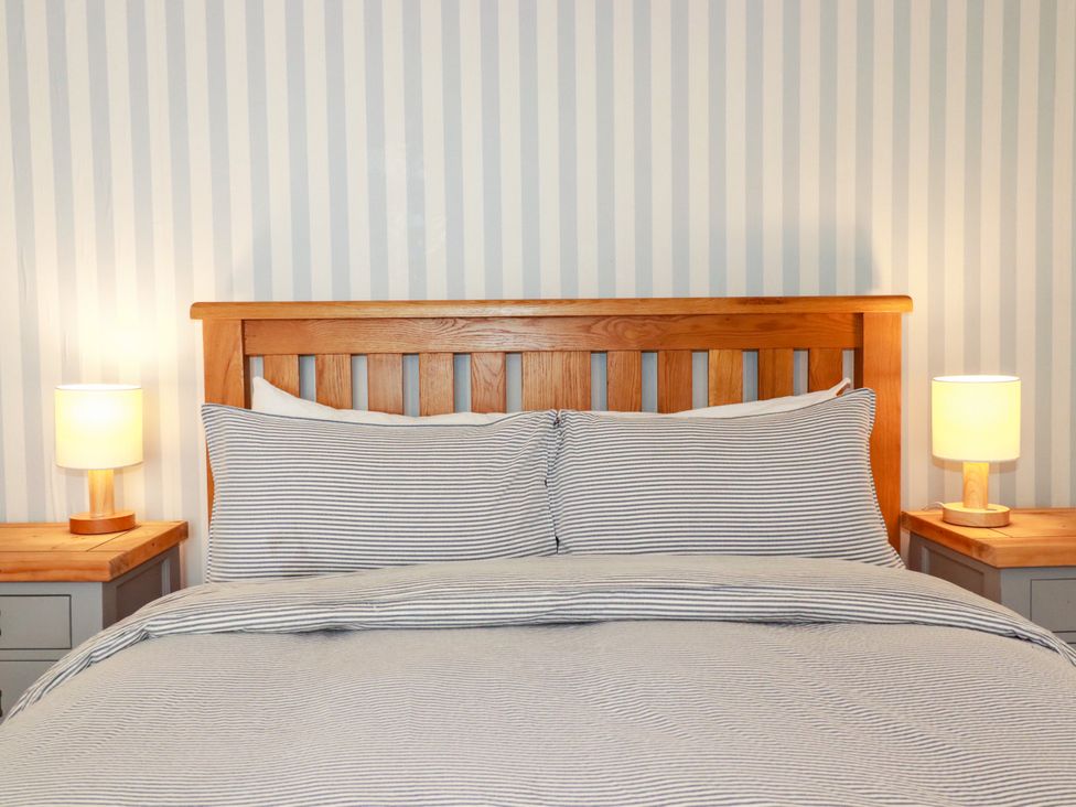 A bedroom with a wooden bed and striped bedding at Dolphin Cottage Flushing