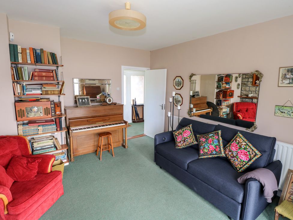 A living room with a piano and bookshelves at Sweetbriar Lodge in Castlerea
