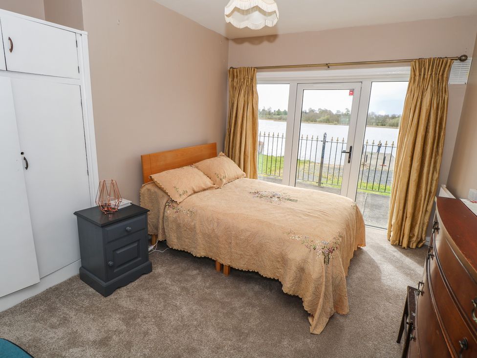 A bedroom with a bed and a view of the water at Sweetbriar Lodge in Castlerea