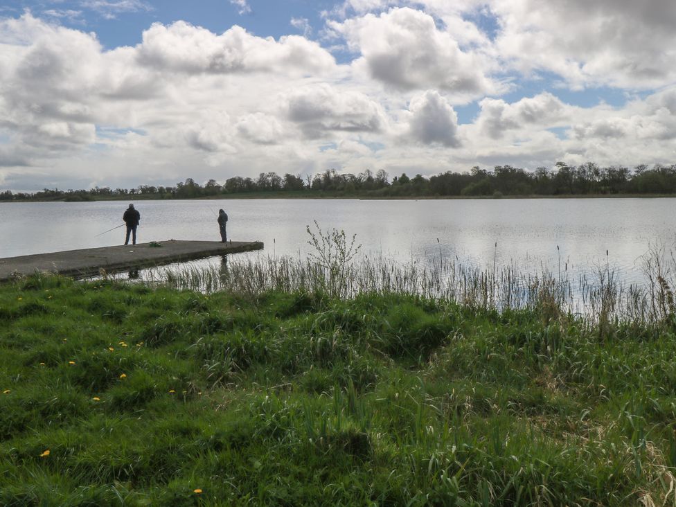 Two people fishing from a pier by a lake at Sweetbriar Lodge Castlerea