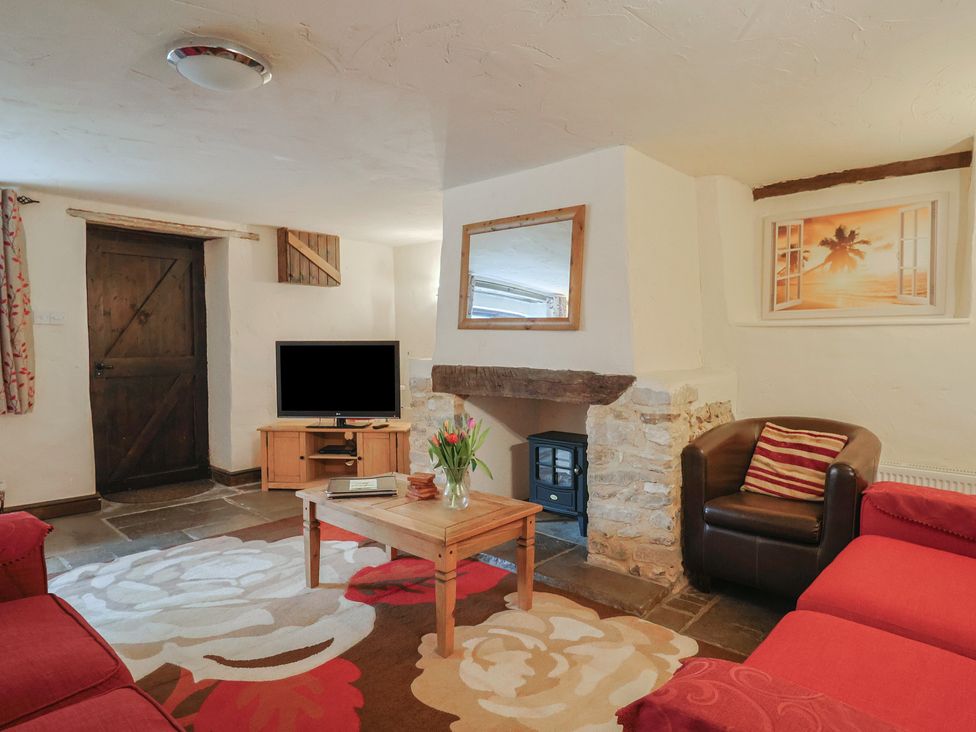 A living room with a television, sofa, and coffee table at Cider Cottage, Hawkchurch