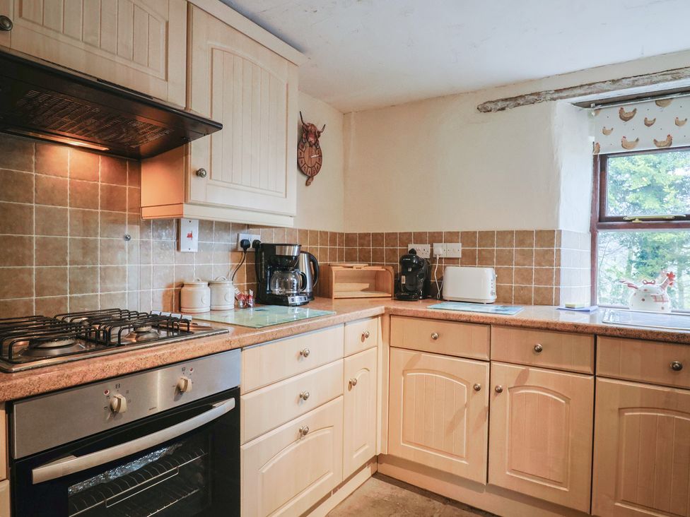 A kitchen with cabinets, oven, sink, and appliances at Cider Cottage in Hawkchurch