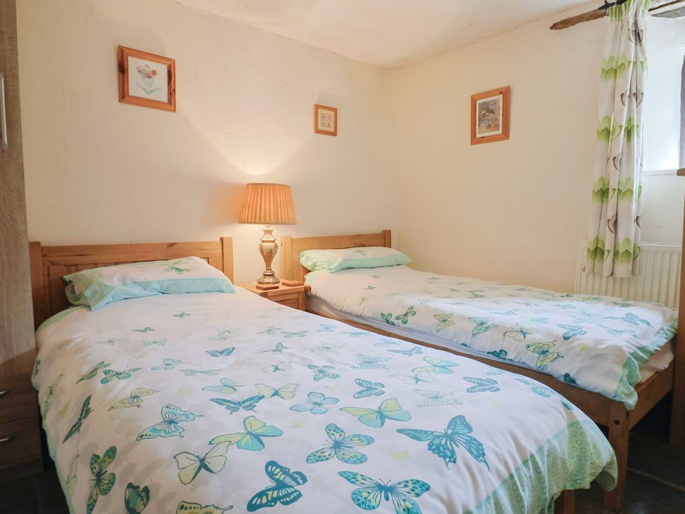 A bedroom with two single beds and a lamp at Cider Cottage in Hawkchurch