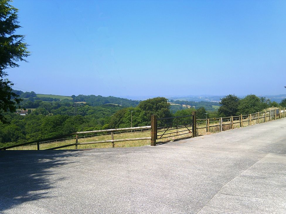 A view of trees and hills from a paved area at Cider Cottage in Hawkchurch