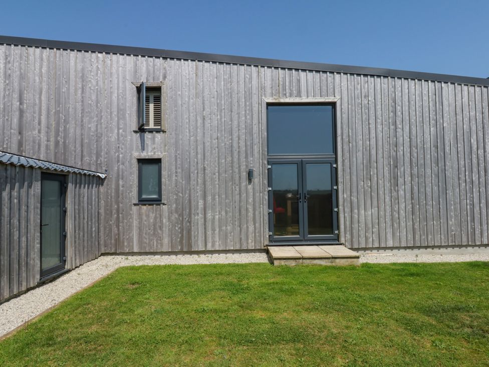 A building with a door and windows in a garden at Fieldstone Barn North Tawton
