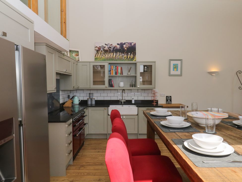 A kitchen with a stove, sink, and dining table at Fieldstone Barn North Tawton
