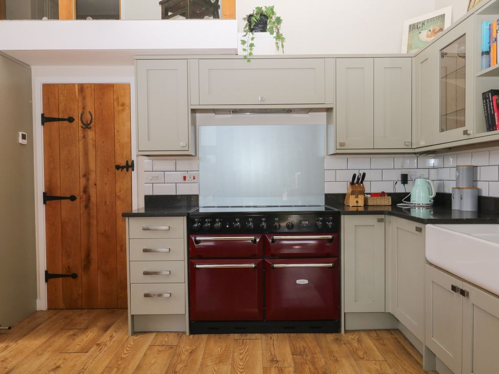 A kitchen with an oven, sink, and cabinets at Fieldstone Barn, North Tawton