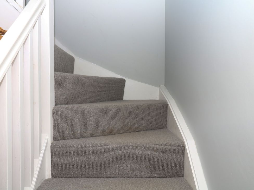A staircase with carpet and handrail at Fieldstone Barn in North Tawton