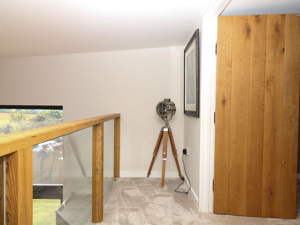 A landing area with a decorative lamp and a wooden door at Fieldstone Barn in North Tawton