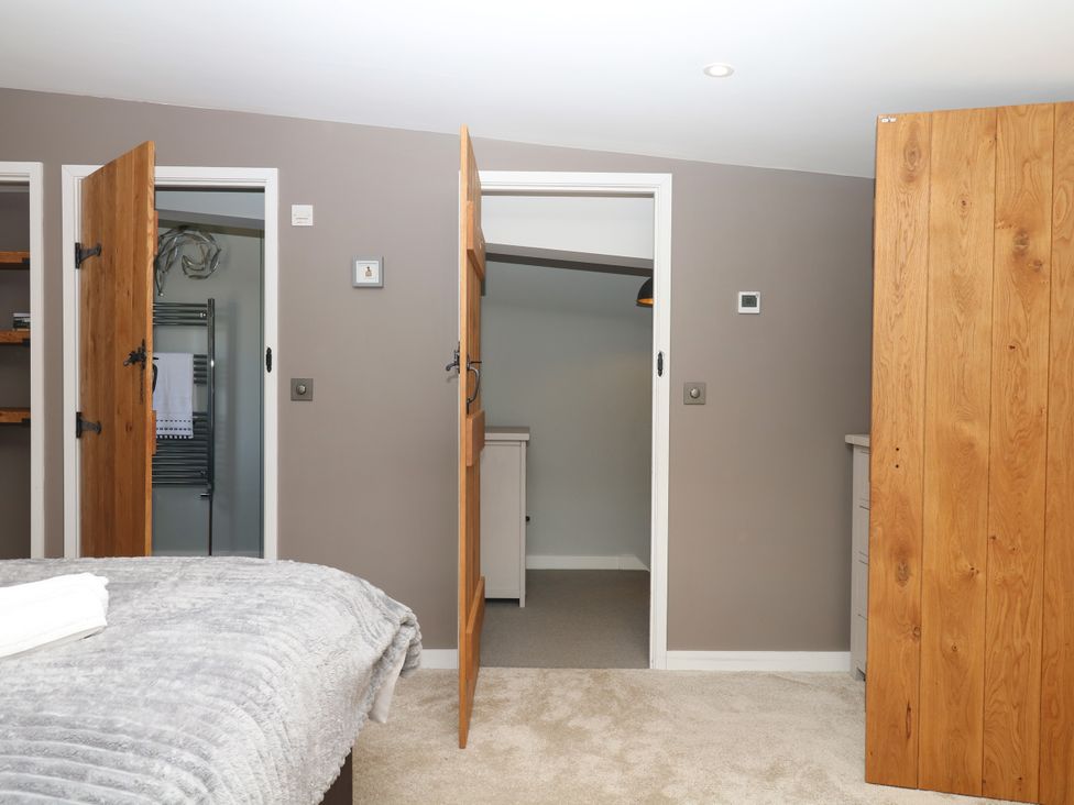 A bedroom with open doors leading to shelves and cabinets at Fieldstone Barn North Tawton