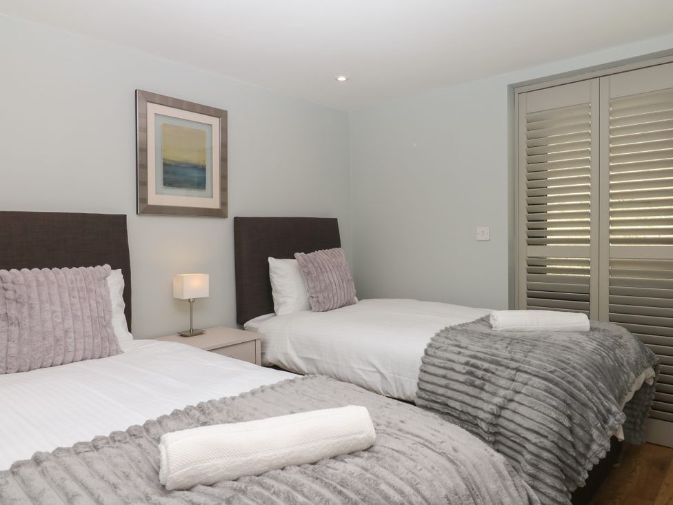 A bedroom with two beds and a lamp on a nightstand at Fieldstone Barn in North Tawton