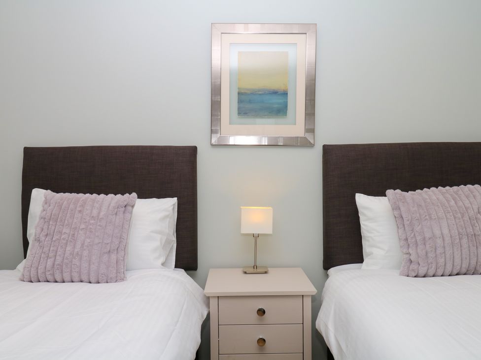 A bedroom with two beds and a nightstand at Fieldstone Barn in North Tawton