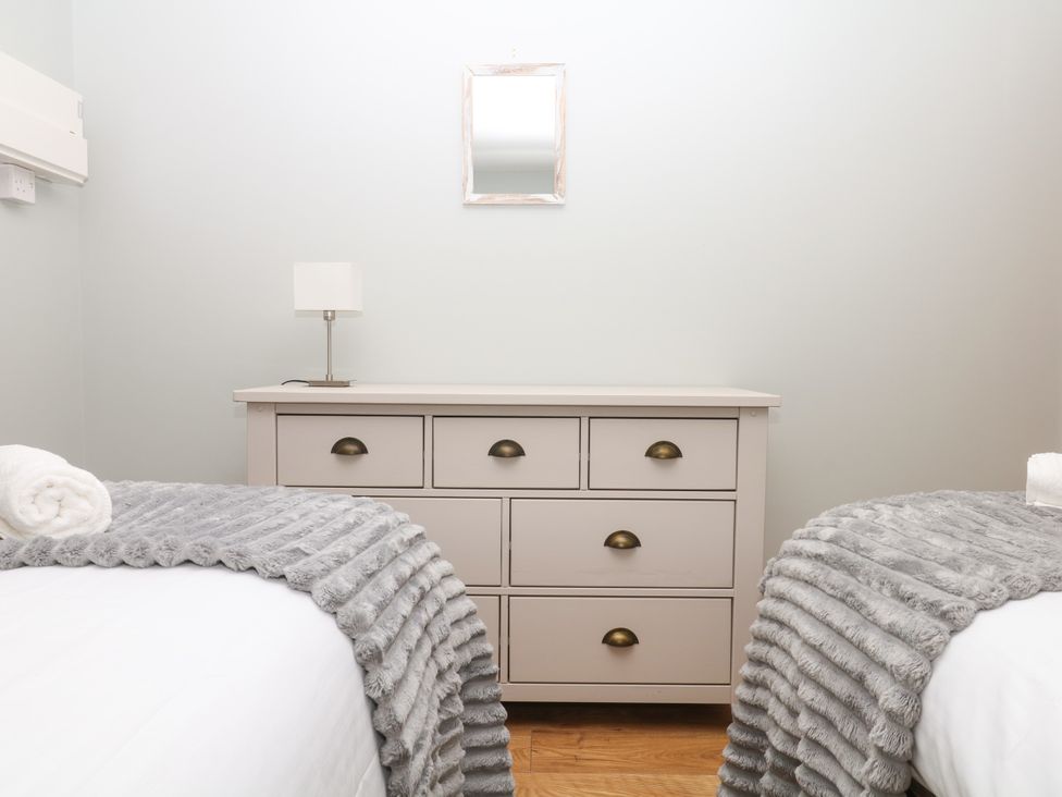 A bedroom with a dresser and two beds at Fieldstone Barn in North Tawton