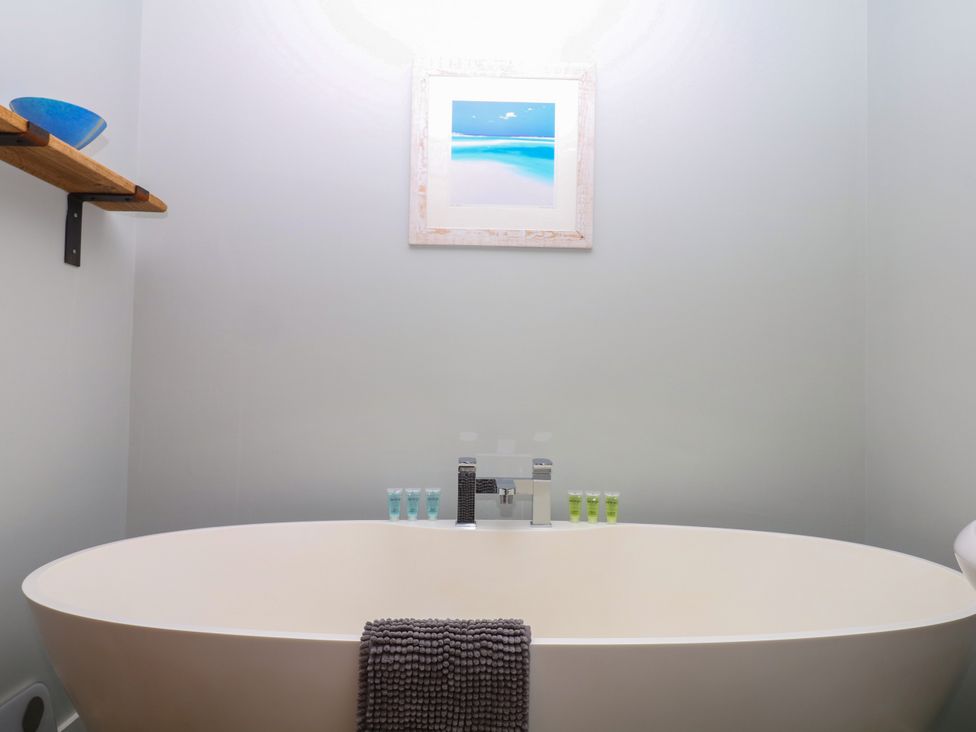 A bathroom with a bathtub and shelf at Fieldstone Barn in North Tawton