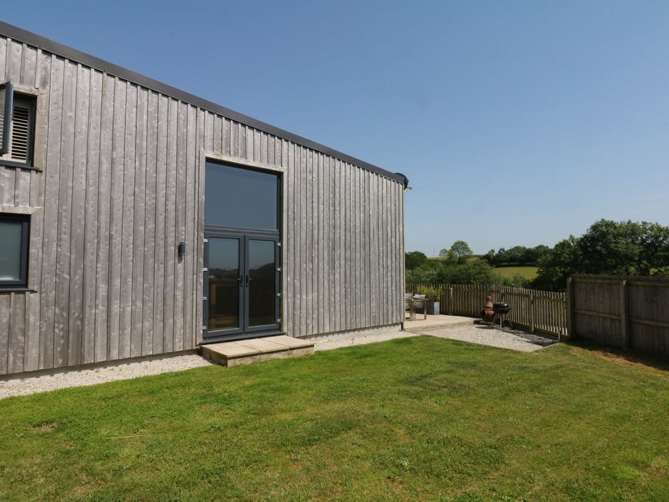 An outdoor area with a wooden building and patio at Fieldstone Barn in North Tawton