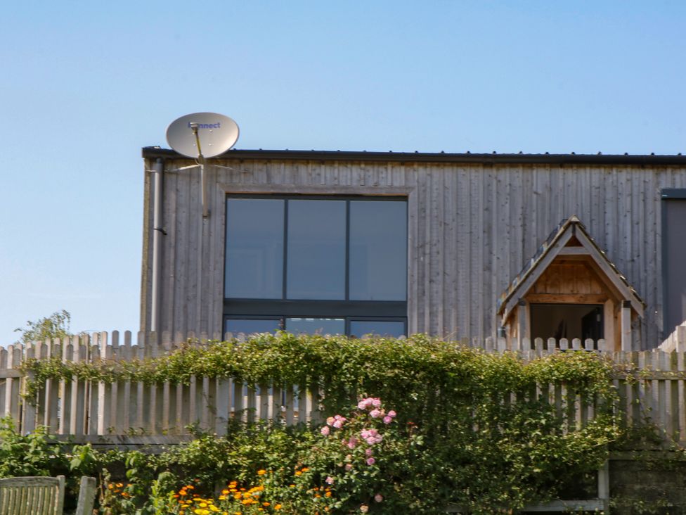 An exterior view of a wooden house with a satellite dish at Fieldstone Barn North Tawton