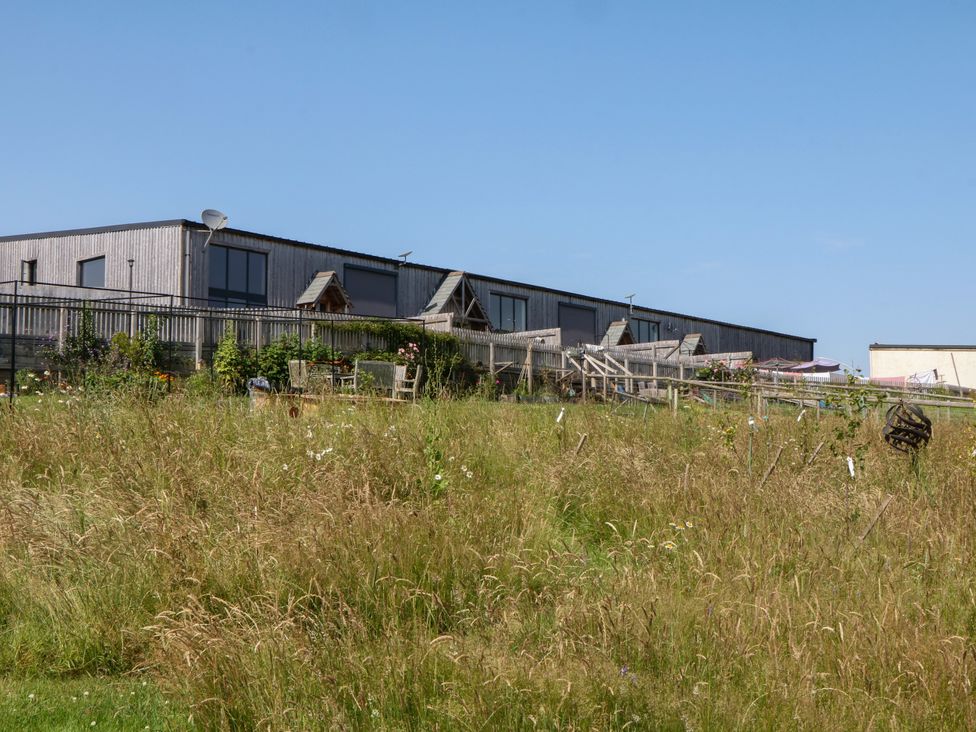 An outdoor area with a building and chairs at Fieldstone Barn in North Tawton