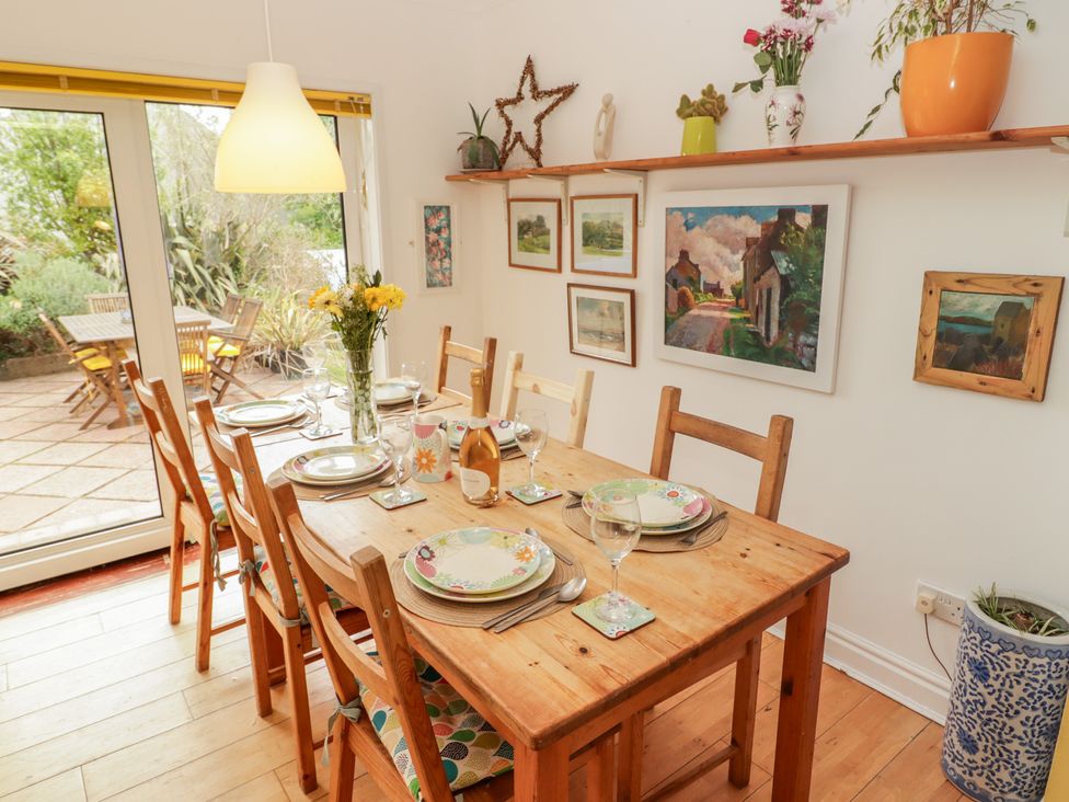 A dining room with a wooden table set for a meal at 1 Rosemount Garden Villas in Tenby