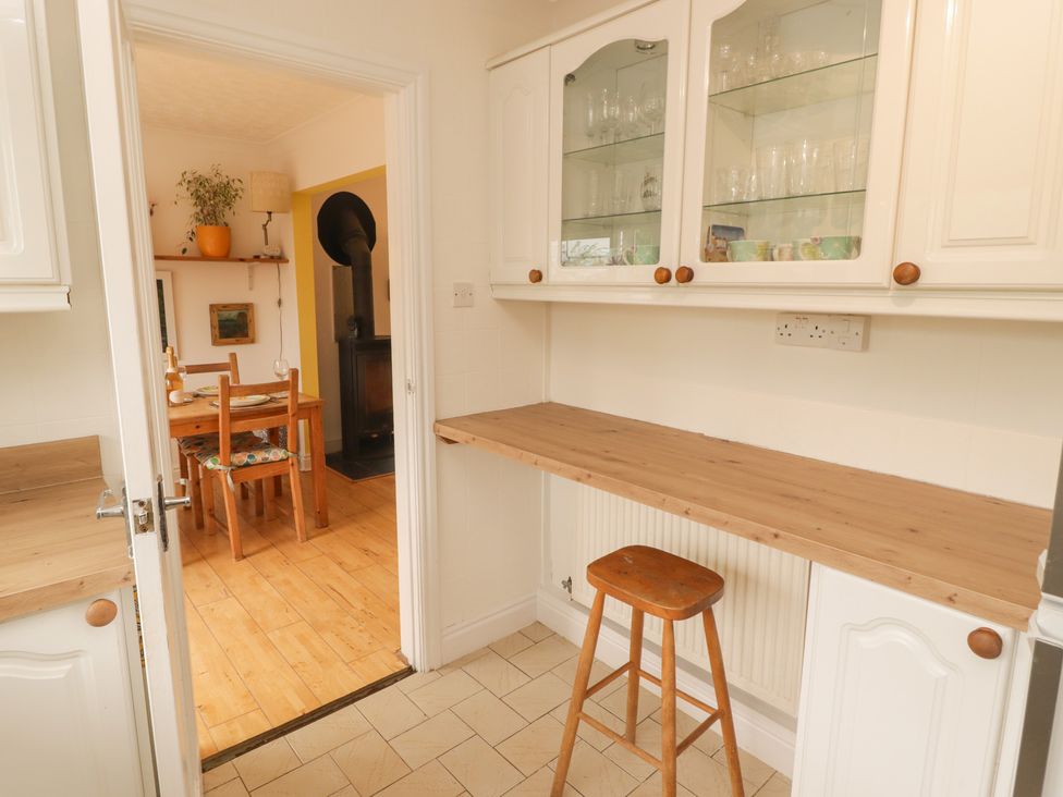 A kitchen with a table and chairs visible in another room at 1 Rosemount Garden Villas Tenby