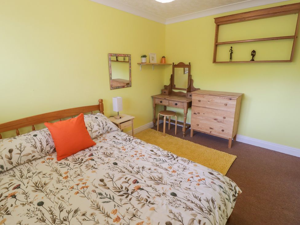 A bedroom with a bed and dressing table at 1 Rosemount Garden Villas Tenby