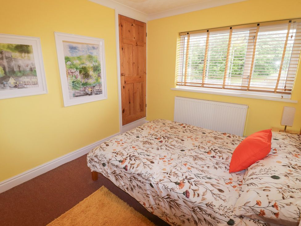 A bedroom with a bed and paintings on the wall at 1 Rosemount Garden Villas Tenby