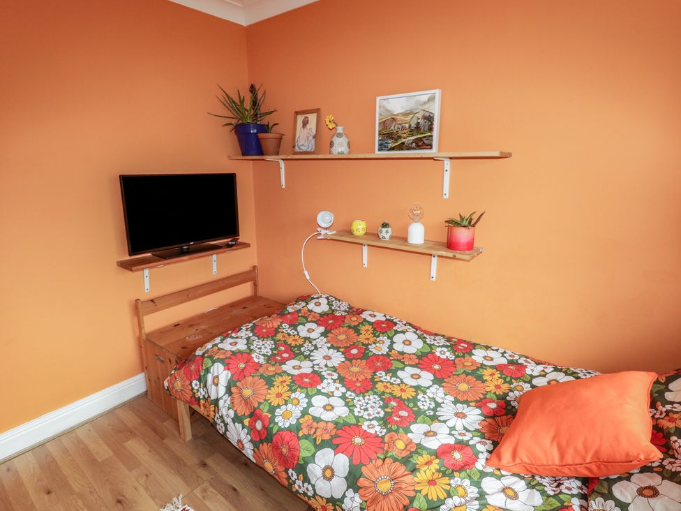 A bedroom with a bed and television at 1 Rosemount Garden Villas in Tenby