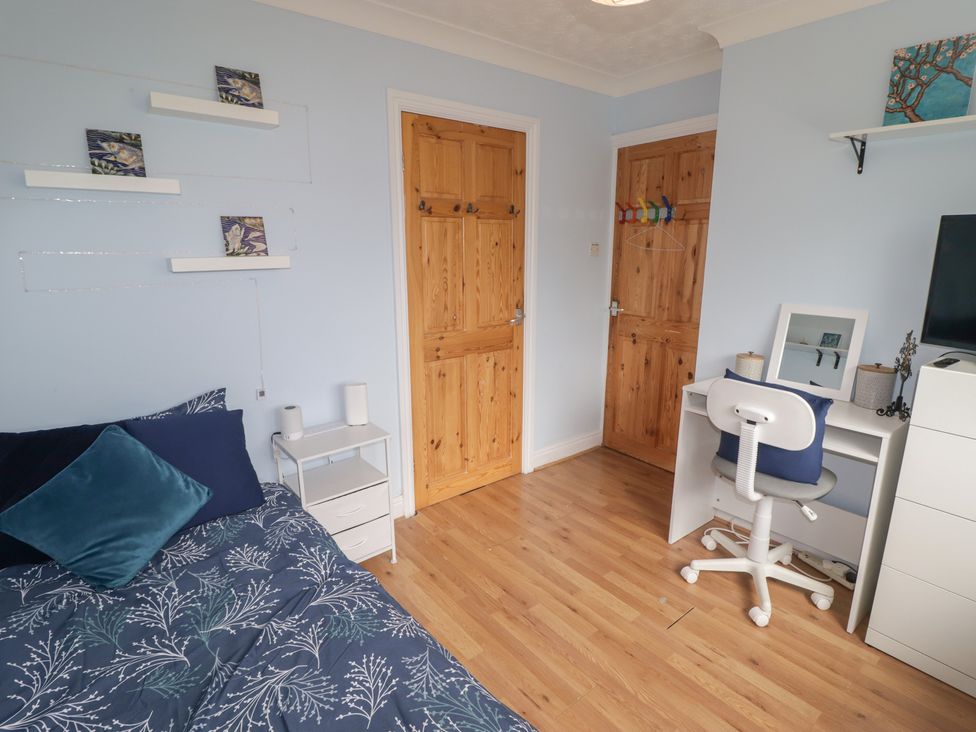 A bedroom with a bed and a desk at 1 Rosemount Garden Villas Tenby