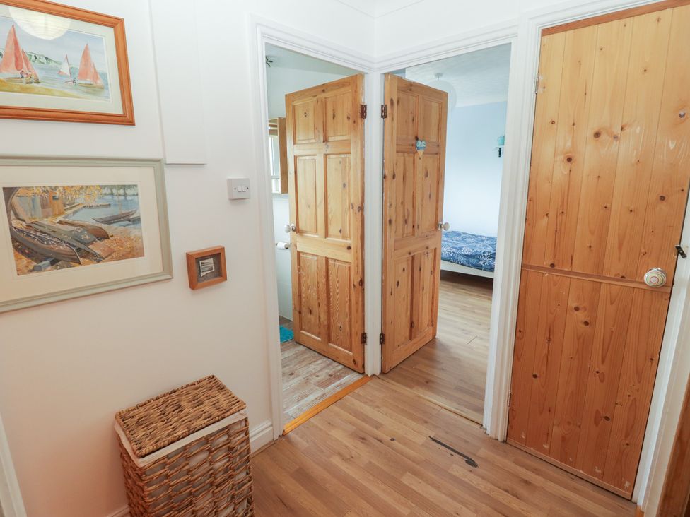 A hallway with wooden doors and a storage basket at 1 Rosemount Garden Villas in Tenby
