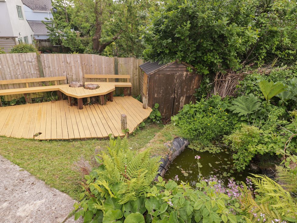 A garden with wooden decking and pond at 1 Rosemount Garden Villas Tenby