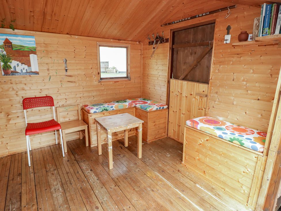 A garden room with a wooden table and benches at 1 Rosemount Garden Villas Tenby