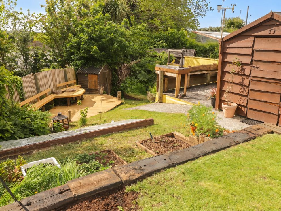 A garden with a wooden bench and a shed at 1 Rosemount Garden Villas Tenby