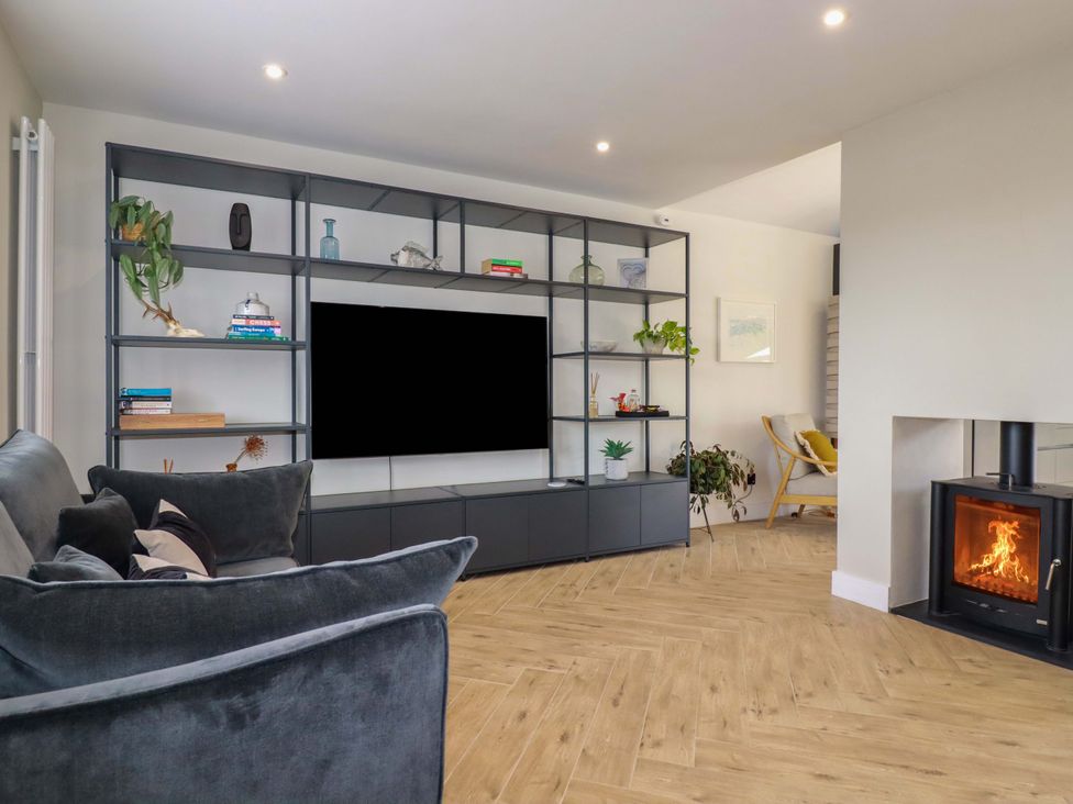 A living room with a television on a shelf and a fireplace at No.45 Whealgolden Drive in Newquay