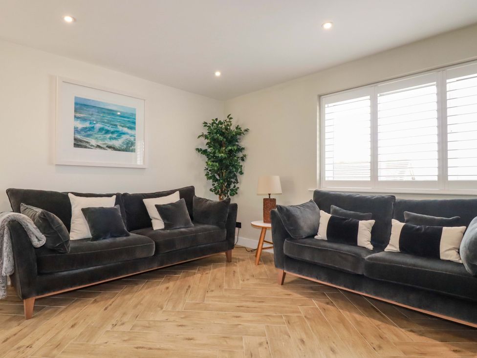 A living room with sofas and a lamp at No.45 Whealgolden Drive in Newquay