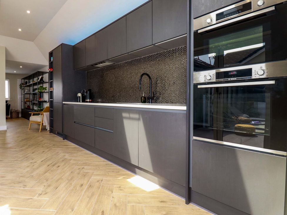 A kitchen with dark cabinetry and appliances at No.45 Whealgolden Drive Newquay