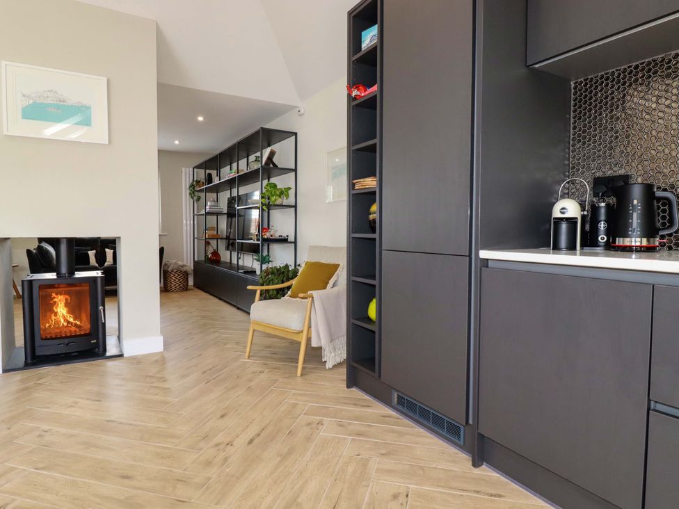 A living room with a fireplace and kitchen area at No.45 Whealgolden Drive Newquay