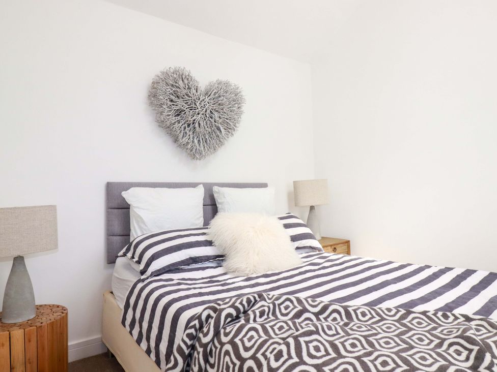 A bedroom with a bed, bedside tables and lamps at No.45 Whealgolden Drive in Newquay
