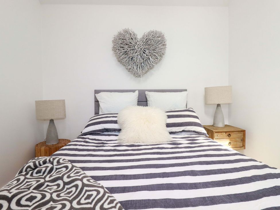 A bedroom with a bed and nightstands at No.45 Whealgolden Drive in Newquay