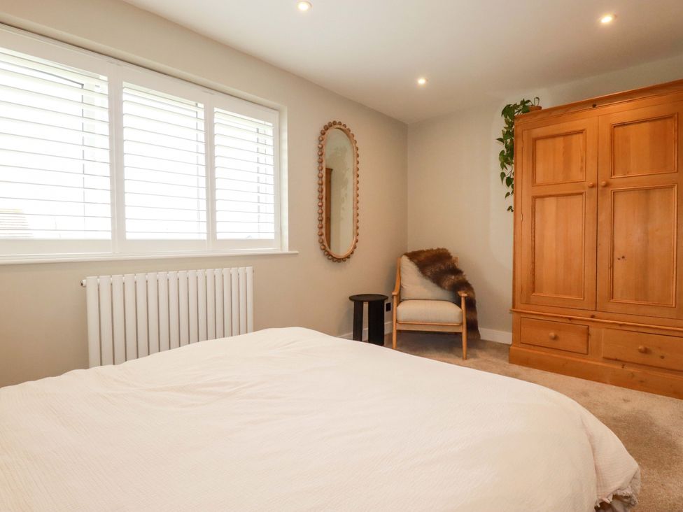 A bedroom with a bed, wardrobe, and armchair at No.45 Whealgolden Drive, Newquay