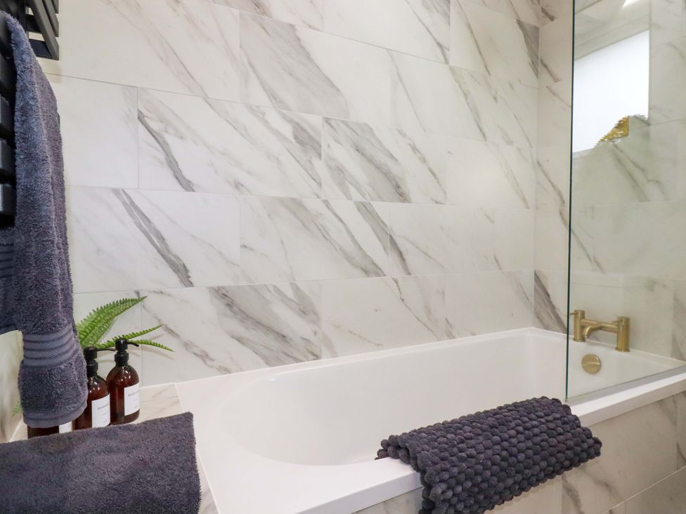 A bathroom with a bathtub and towels at No.45 Whealgolden Drive in Newquay