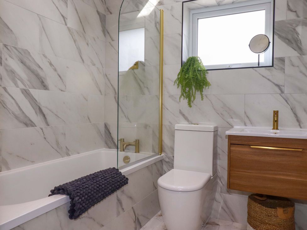 A bathroom with a bathtub, toilet, and sink at No.45 Whealgolden Drive in Newquay