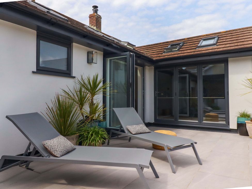 An outdoor patio with lounge chairs and potted plants at No.45 Whealgolden Drive Newquay
