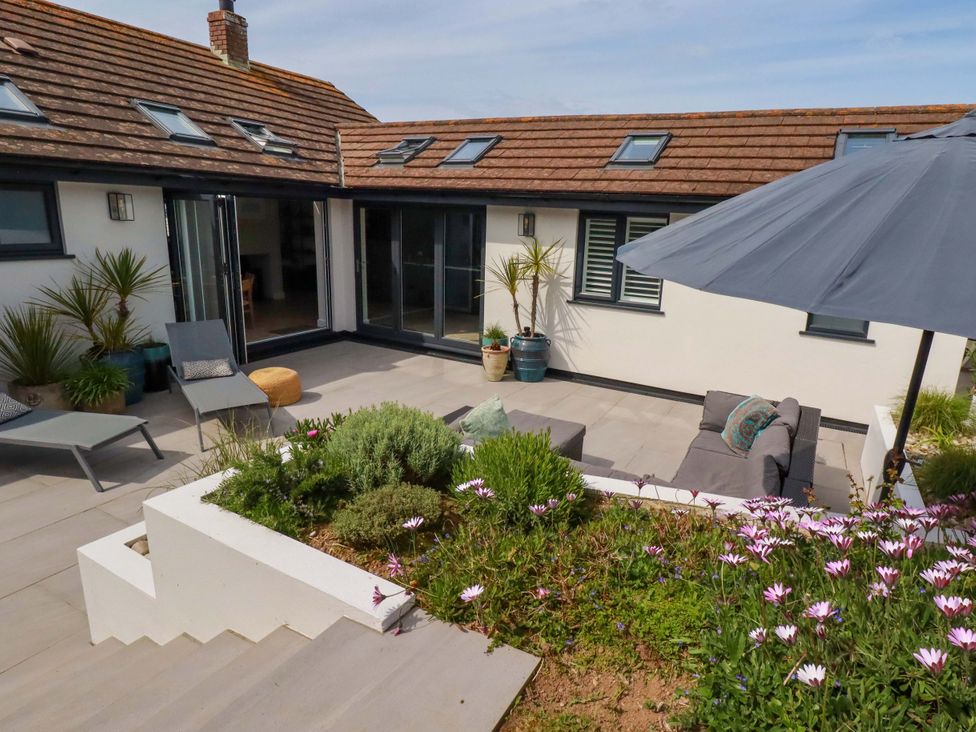 A patio with a sofa and umbrella at No.45 Whealgolden Drive in Newquay