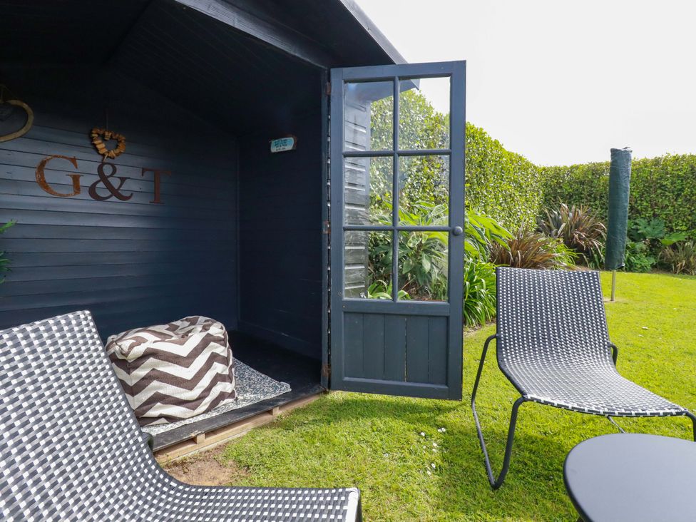 A garden with outdoor seating and a wooden shed at No.45 Whealgolden Drive Newquay