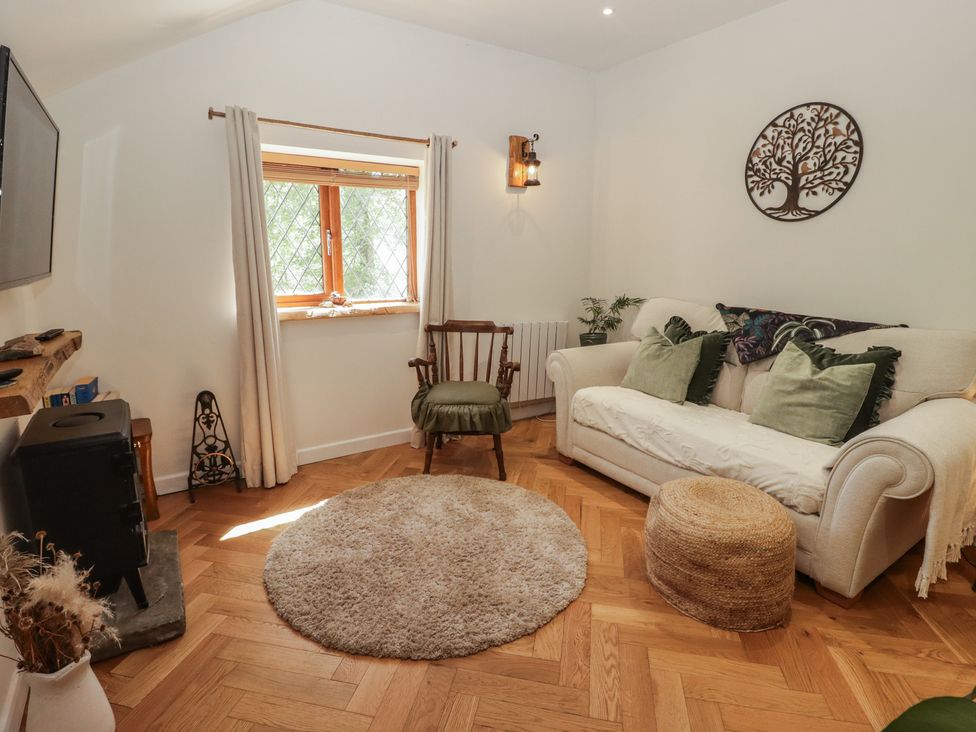 A living room with a sofa and an armchair at Cân adar in Llangeinor