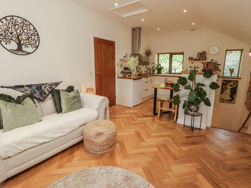 A living room with a sofa and kitchen area at Cân adar in Llangeinor