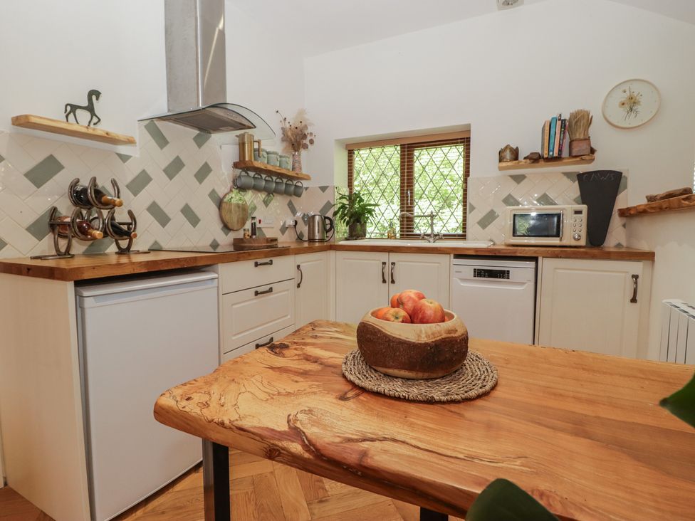 A kitchen with a table and apples at Cân adar in Llangeinor