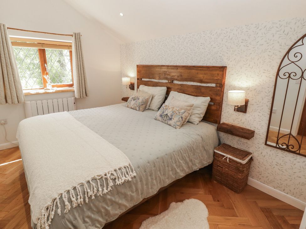 A bedroom with a wooden bed and window at Cân adar in Llangeinor